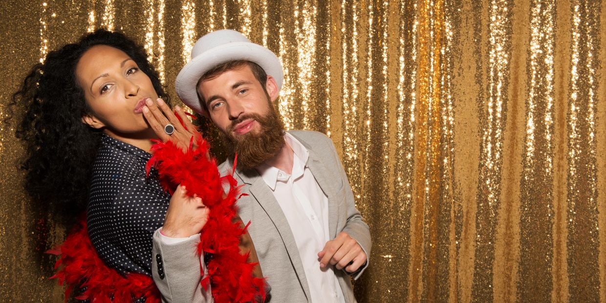 Couple posing playfully in front of gold sequin backdrop.