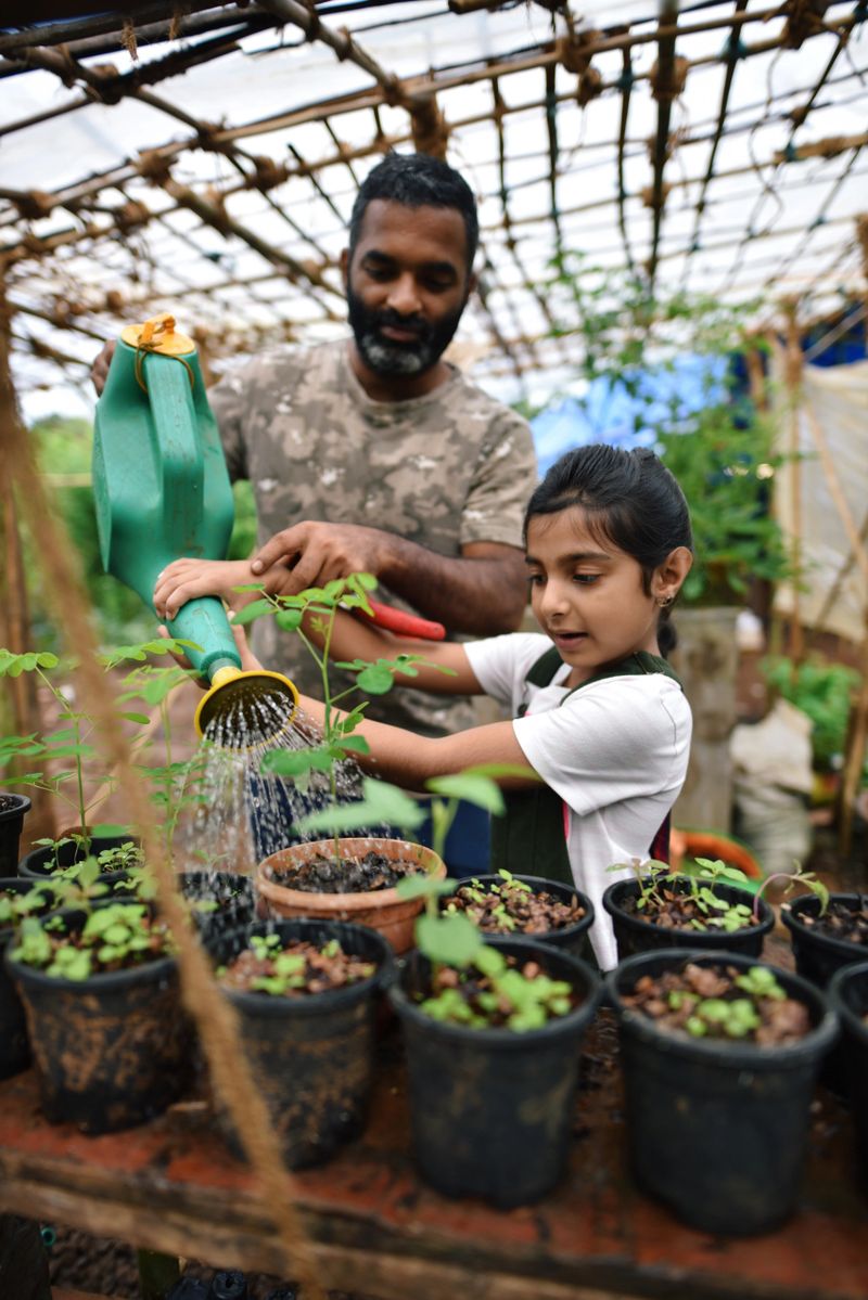 Father and daughter watering the plants in the greenhouse