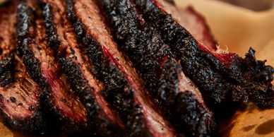 Sliced smoked brisket with a charred crust.