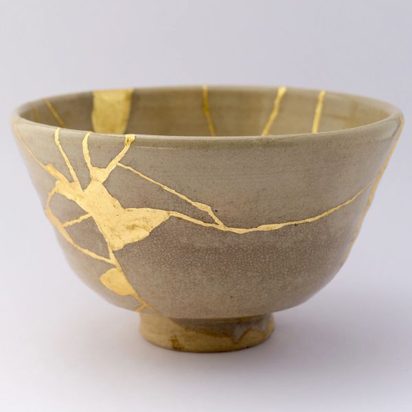 A beige bowl with gold kintsugi cracks