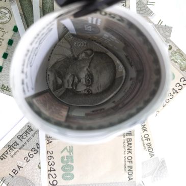 Rolled Indian currency note showing Mahatma Gandhi's portrait.