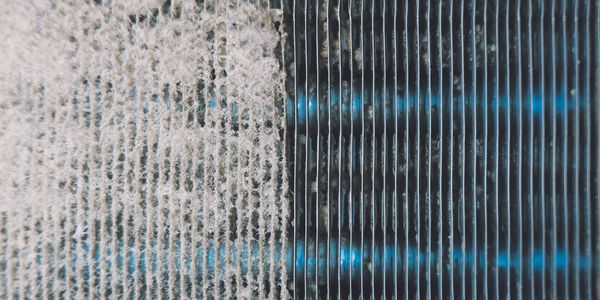 Close-up of a dusty and clean air filter side by side.