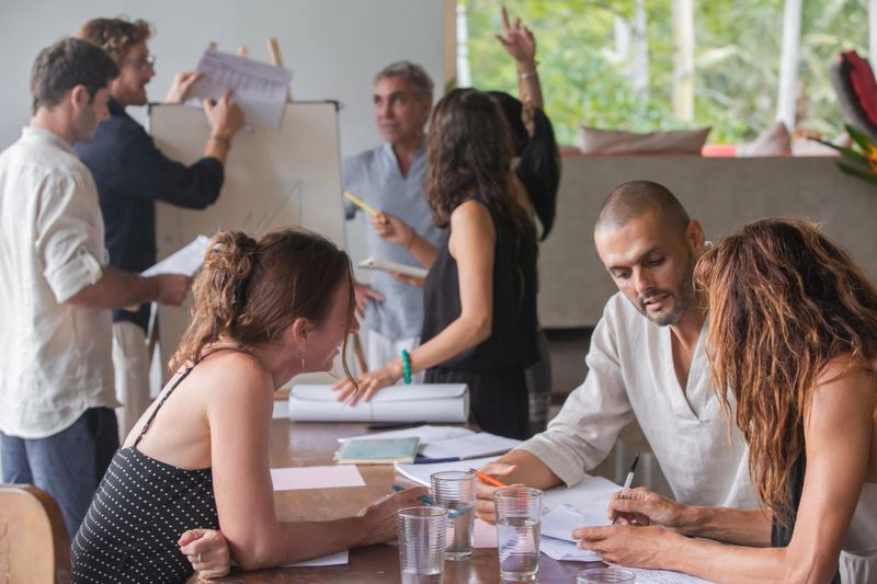 Diverse group of multiethnic people having business meeting, seminar or presentation outdoor in tropical conference. Team members listening attentively to a cheerful speaker holding a presentation