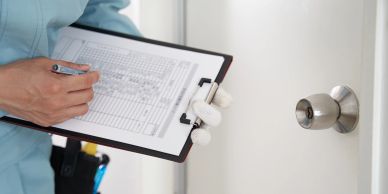 Person filling a checklist on a clipboard by a door.