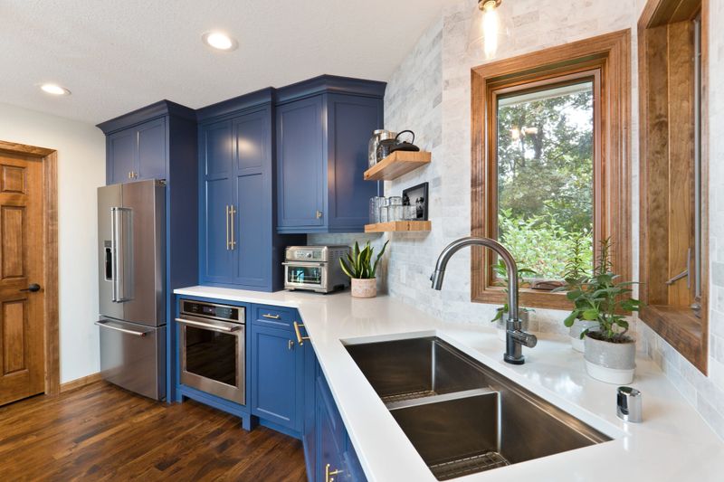 A contemporary kitchen renovation remodeling featuring a hardwood floor  kitchen sink, appliances and quartz counter top.