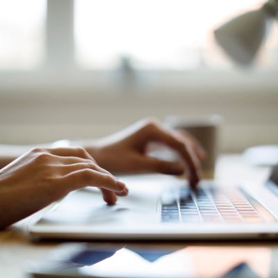 Person typing on a laptop keyboard.