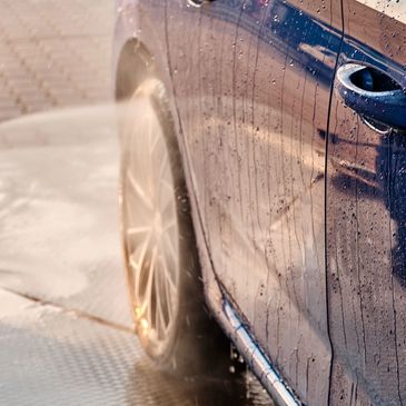 Car being washed with a high-pressure water spray.