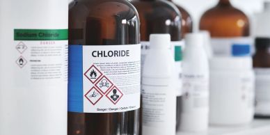 Chemical bottles with hazard labels in a lab.