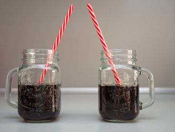 Two mason jars filled with soda and striped straws.