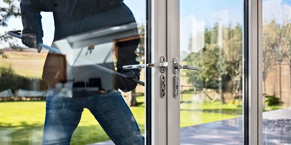 Masked burglar breaking into a house using a crowbar.