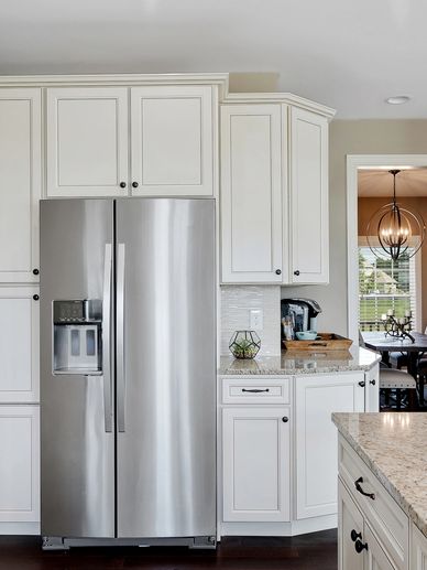 Modern kitchen with stainless steel refrigerator and white cabinetry.