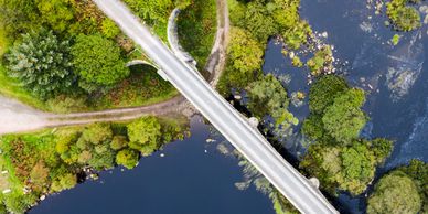 Aerial view of a bridge over a river surrounded by lush green trees.