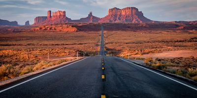 Scenic Arizona highway stretching into the horizon at sunset, with warm light on a desert landscape