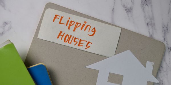 Notebook labeled 'Flipping Houses' with house cutout and colorful books.