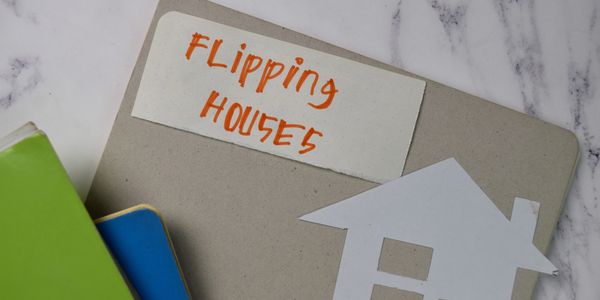 Notebook labeled 'Flipping Houses' with house cutout and colorful books.