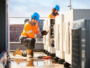 Two technicians working on rooftop HVAC units.