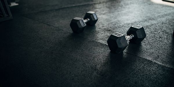 Two dumbbells resting on a gym floor under natural light.