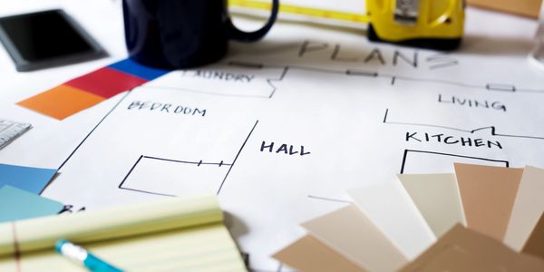 Architectural plans with color swatches and measuring tools on a desk.