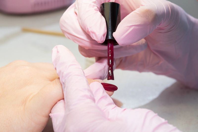 Applying colored nail Polish to the client's nails during the manicure process.