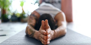 Person stretching forward on a yoga mat with hands clasped.