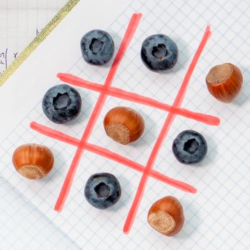 Noughts and crosses game being played using conkers and blueberries.