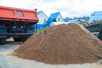 Large pile of sand near a truck in a rural area.