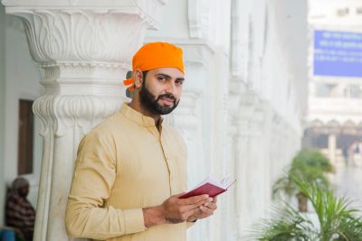 Man in orange headscarf holding a book.
