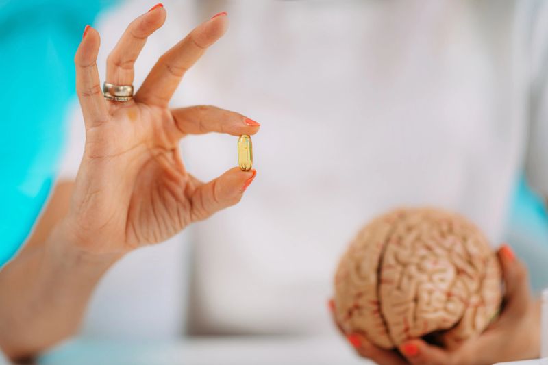 Cognitive improvement or brain supplements. Woman holding a supplement capsule and a model brain.