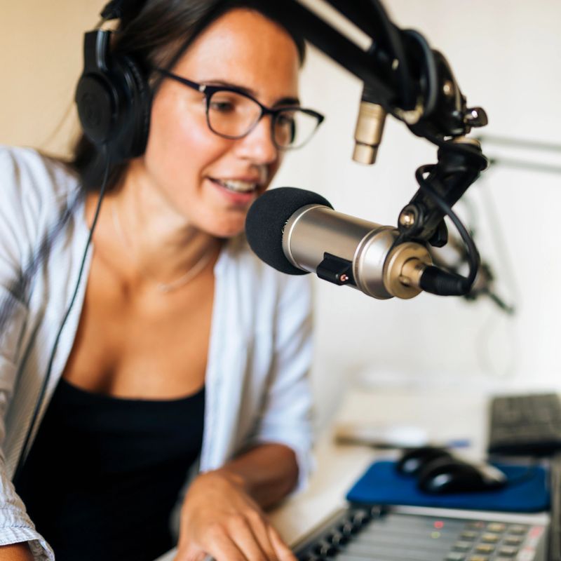 Attractive young woman wearing headphones and talking at online radio station talk show