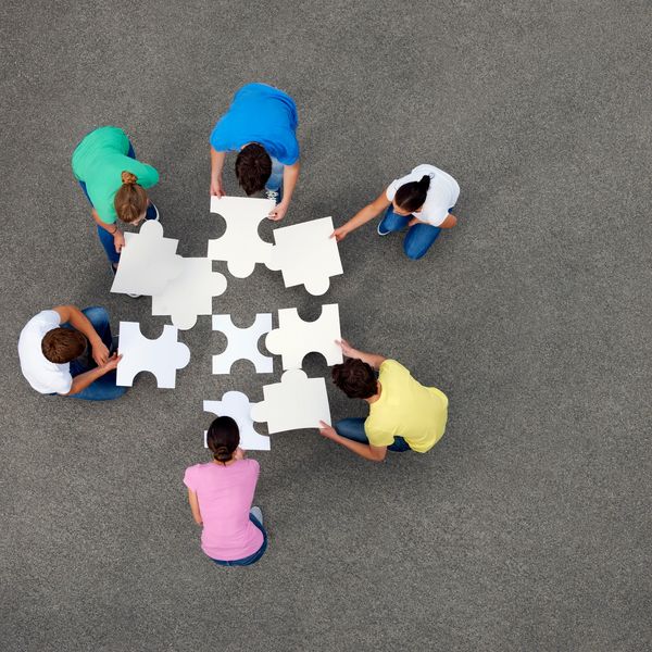 Group assembling large puzzle pieces on the ground.
