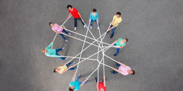 People standing in a circle holding ropes creating a star shape.