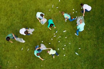 Group of people cleaning up litter on a grassy field.