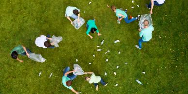 People cleaning up trash on a grassy field.