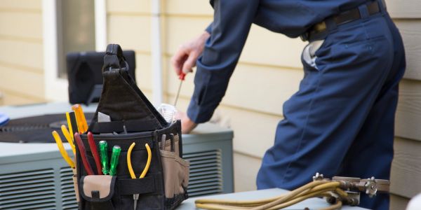 HVAC technician with tools working on an air conditioner.