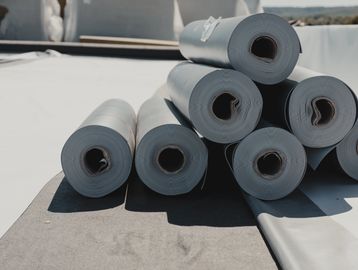 Rolled white plastic sheets stacked outdoors.