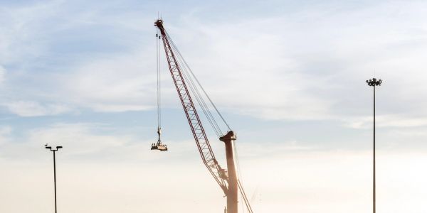 A crane lifting cargo containers at a shipping yard.