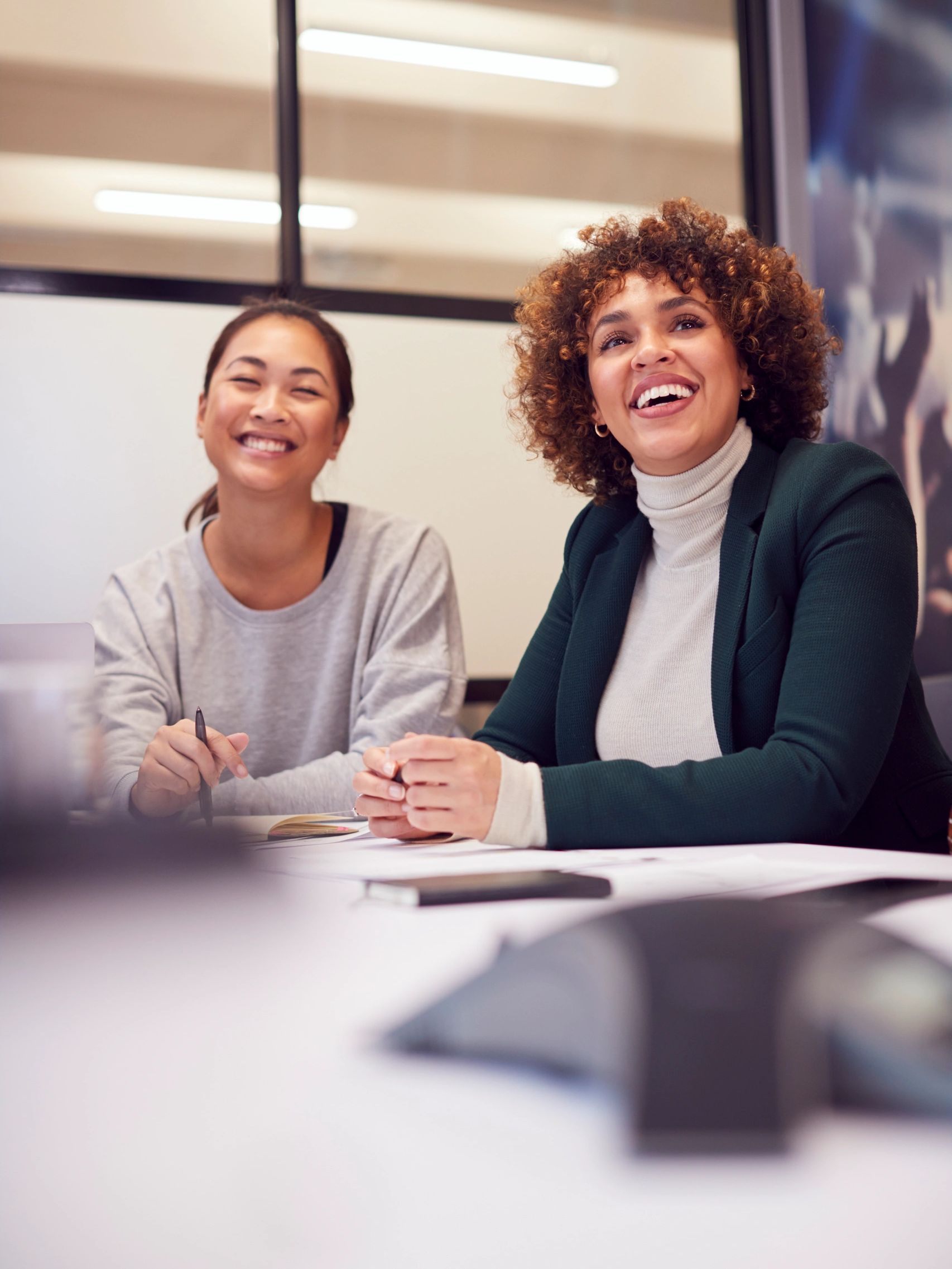 Two women smiling during a meeting or study session.