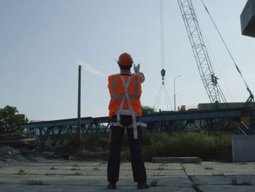 Construction worker guiding a crane at a building site.