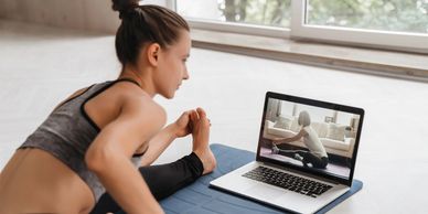 Woman practicing yoga at home following an online video on her laptop. Jenny Von Jenny Wellness