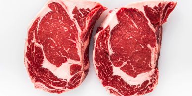 Two raw ribeye steaks with marbling.