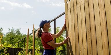 Person installing wooden panels outdoors.