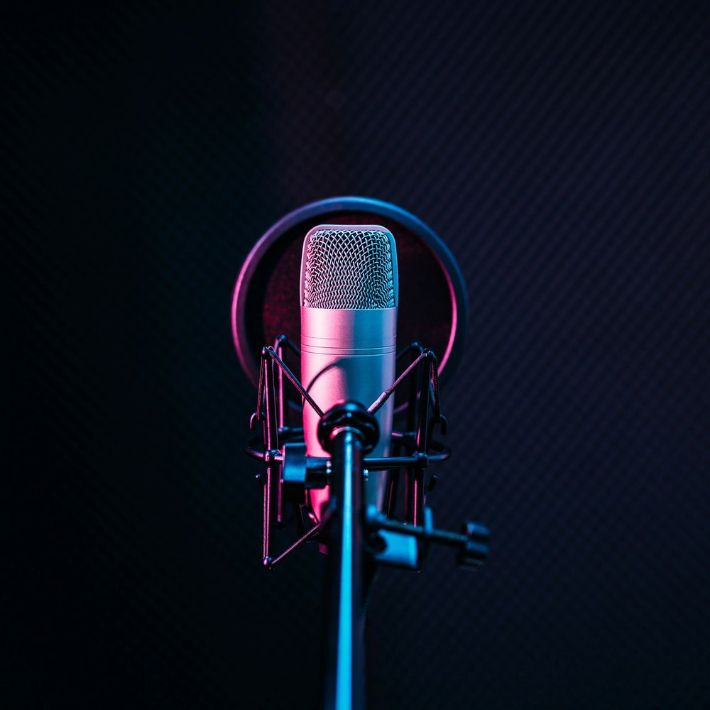 Studio microphone with colorful lighting on a dark background.