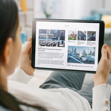 Person reading news on a tablet at home.