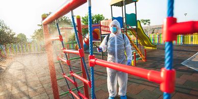 Persona desinfectando un parque infantil.