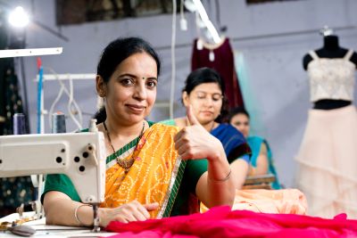 Woman showing thumbs up while sewing.