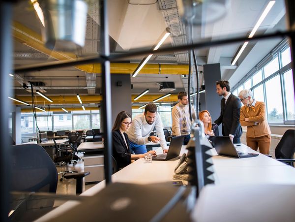 Team meeting in a modern office with laptops and collaborative discussion.