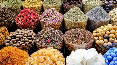 Colorful spices and herbs neatly displayed in transparent containers at a market.