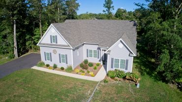 A single-story house with gray siding surrounded by trees and a manicured lawn.