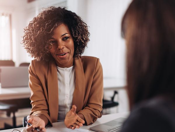 A professional woman discussing documents with a colleague in an office setting.