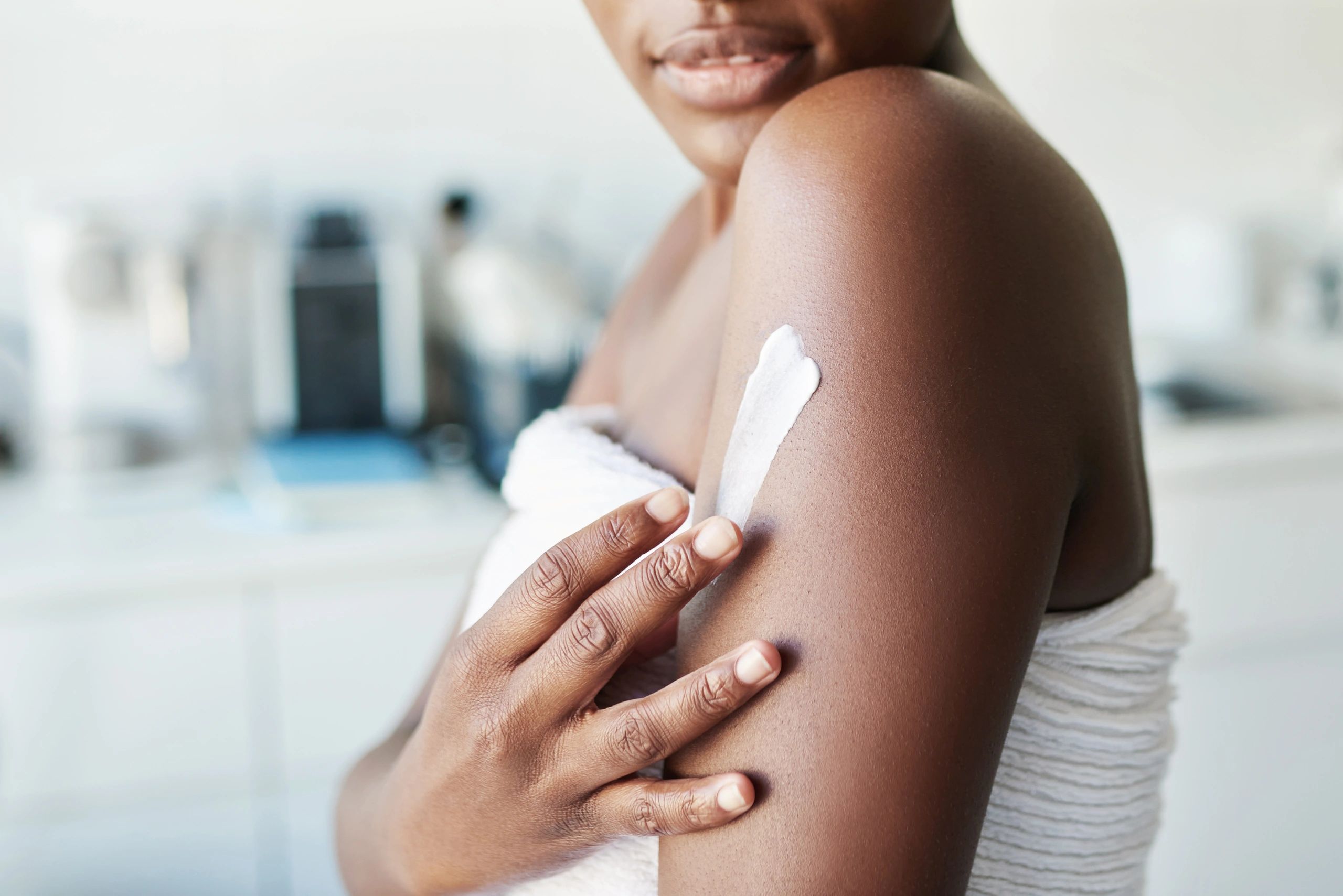 Woman applying lotion on her shoulder.
